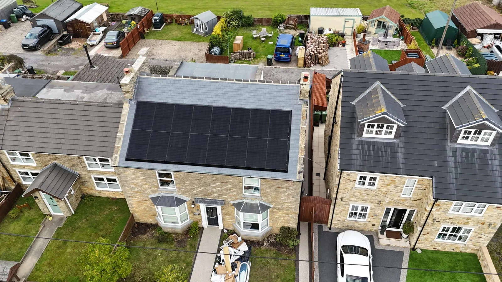 Aerial view of black solar panels on a UK residential rooftop in a stone-built street