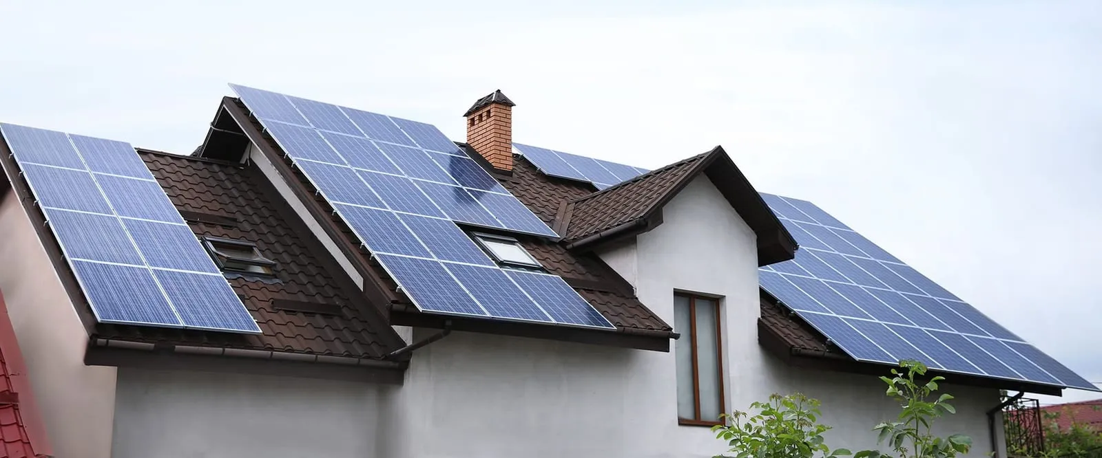 Blue solar panels installed across the pitched roofs of a UK detached house